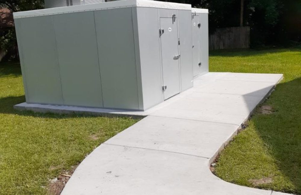 A sidewalk leading to walk in refrigerator outside on a lawn